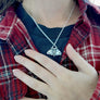silver mothman charm being worn against a black tshirt