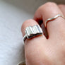 dainty silver book ring being worn as pinky ring
