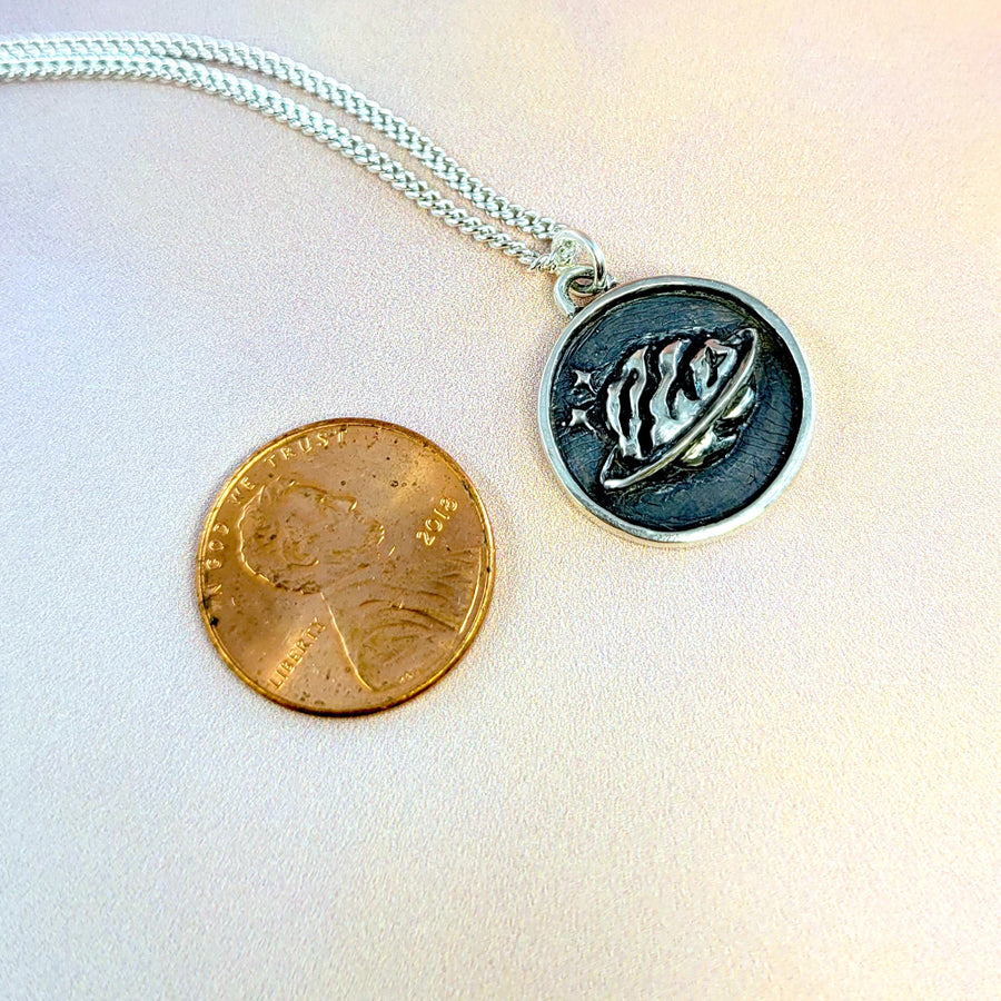 brain pendant next to penny to show smaller size
