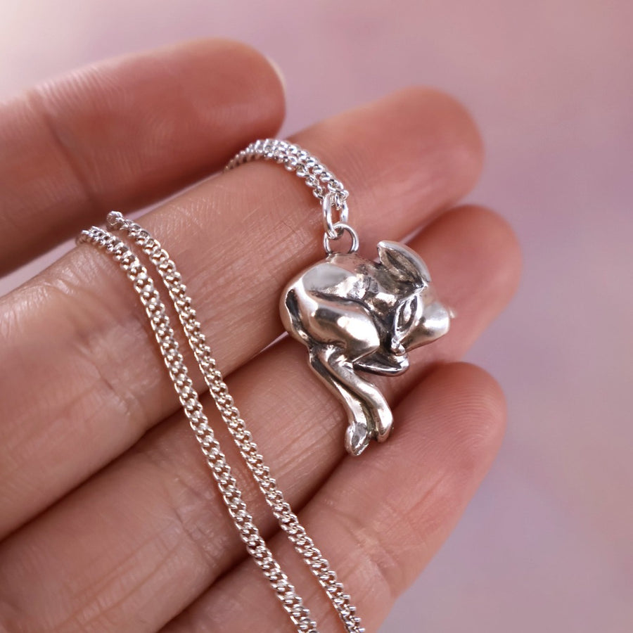 tiny deer pendant in hand, to show small scale